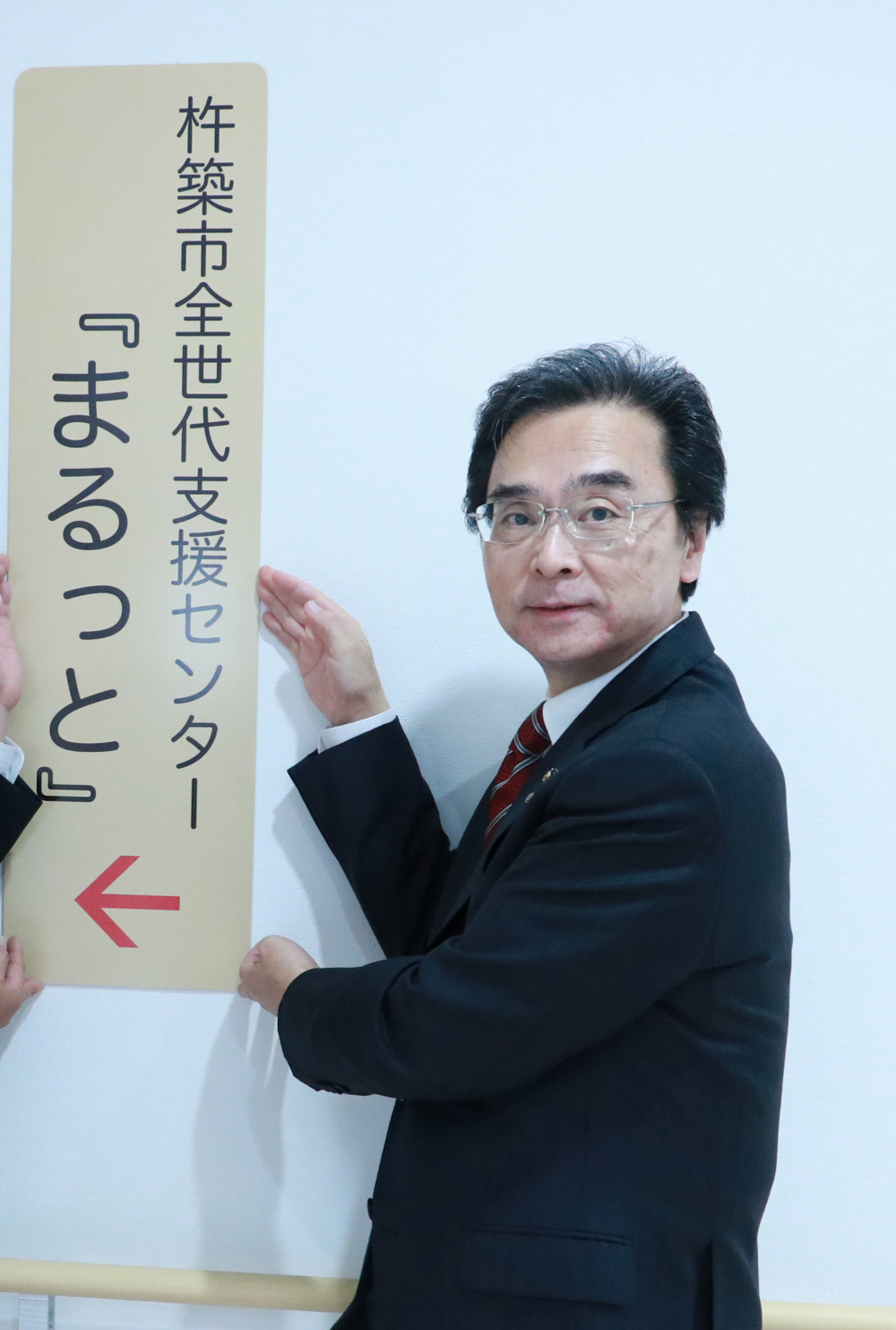「杵築市全世代支援センター『まるっと』」の案内看板を手に持つ杵築市永松市長。